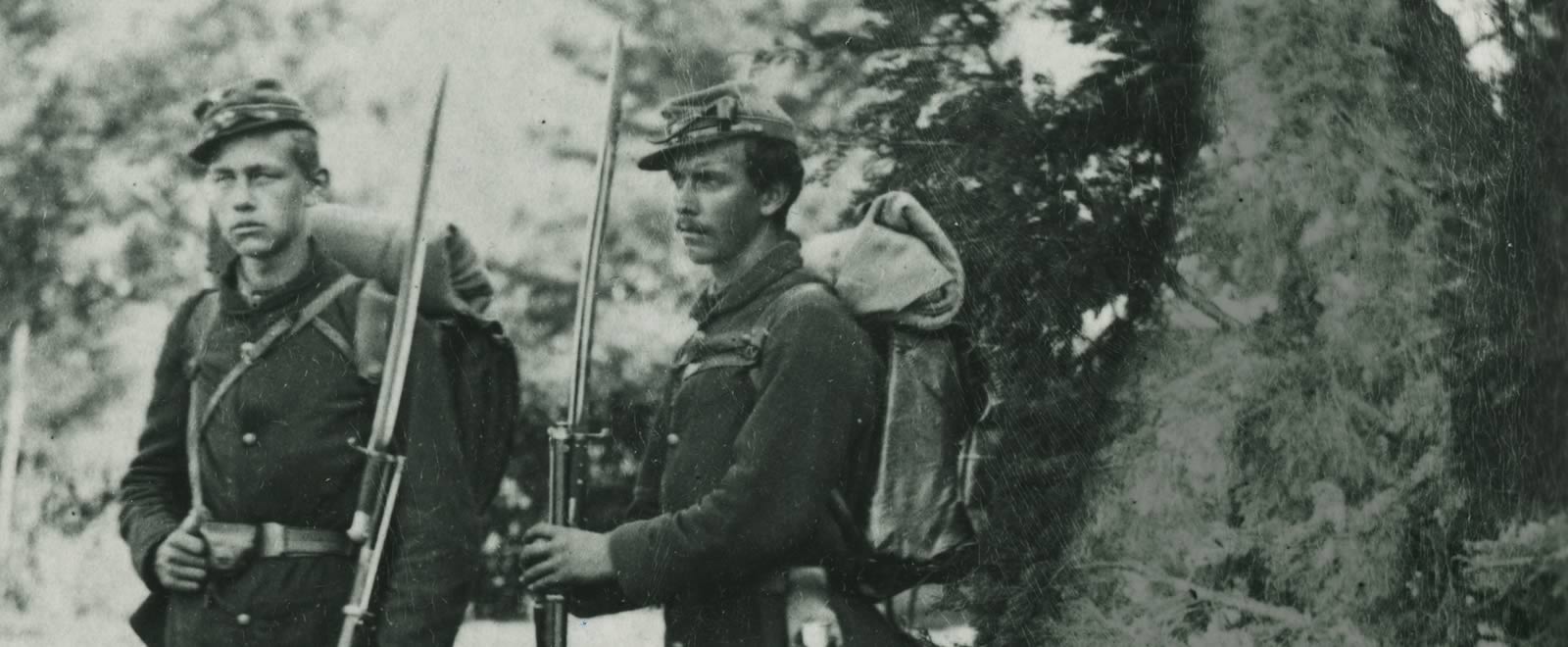 Two American Civil War soldiers standing by a large tree
