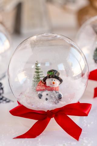 small snow glove with a snow man inside of it and a red ribbon tied around the base