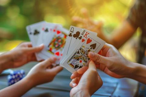 four hands grab at the same set of playing cards