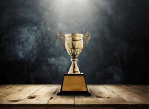 a single trophy sits on a stage illuminated by a spotlight