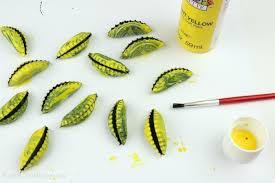 bottle caps bent in half with yellow paint on them plus a paintbrush