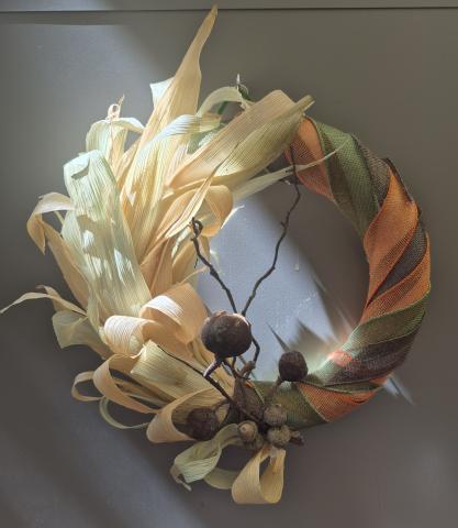 wreath made out of corn husks and colored burlap ribbon