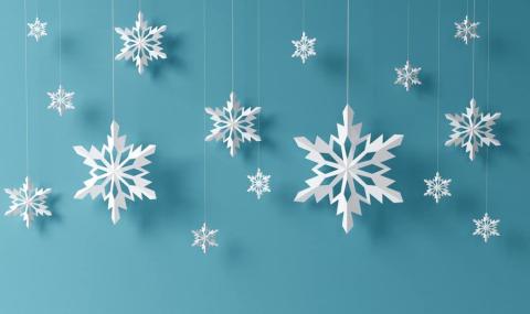 paper snowflakes of various sizes, shapes, and designs dangle by white floss in front of a blue back ground