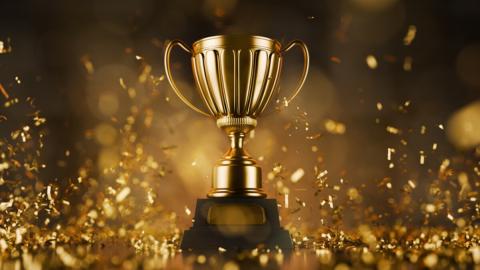 a single trophy sits on a stage illuminated by a spotlight