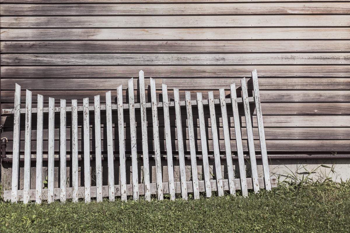 section of old wooden fence leaning up against a wooden house