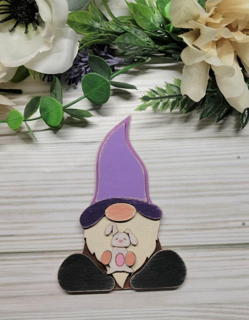 painted flat plaque of a gnome holding a bunny rabbit