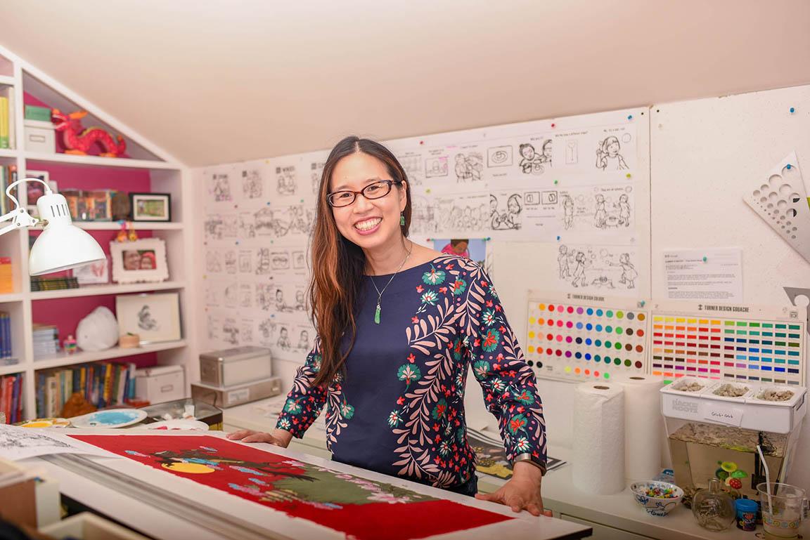 a smiling Grace Lin standing in her art studio