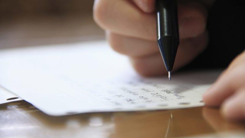 a close up shot of a hand holding a pen, the person is about to continue writing on a single sheet of paper