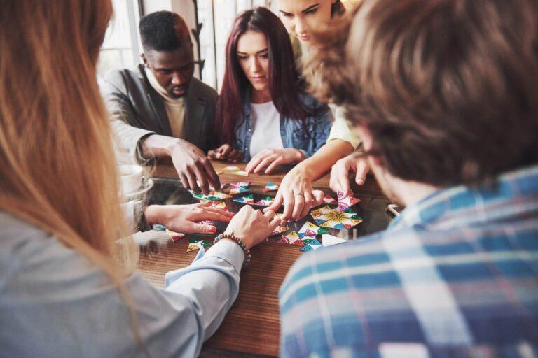 teens crowded around a table play a brightly colored board game