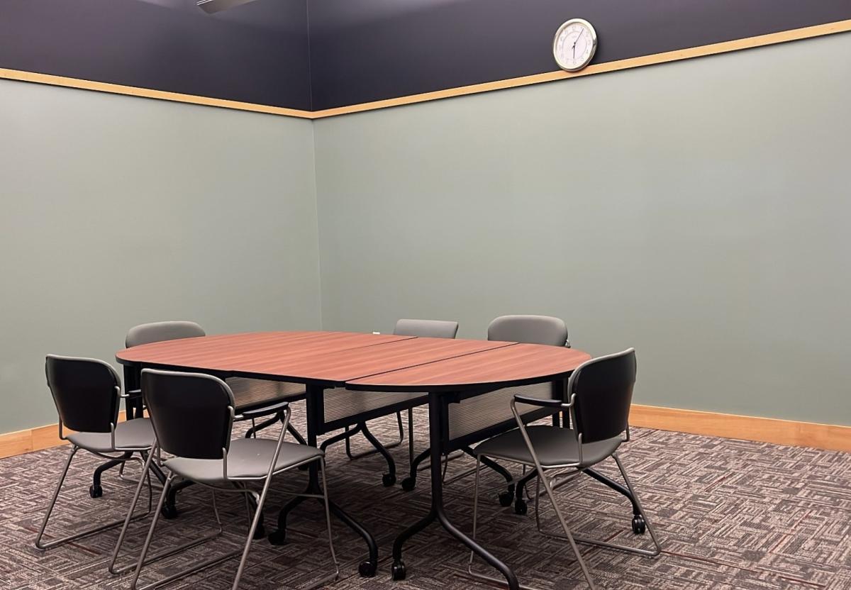 photo of empty conference room with green walls, carpet, a small conference table and 6 chairs